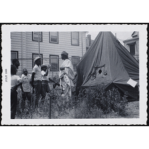 A group of boys stand outside a tent pitched in a yard during Tom Sawyer Day