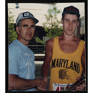 Runner Derek Gallagher accepts a trophy and handshake from a man during the Battle of Bunker Hill Road Race