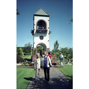 Two female Chinese Progressive Association members pose in front of a bell tower in a Vancouver park