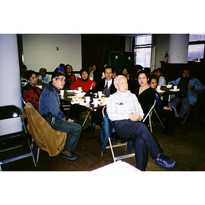 Guests turn in their seats, listening to someone speak at the conclusion of Thanksgiving dinner