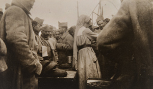 Red Cross worker serving bread and coffee to a crowd of soldiers