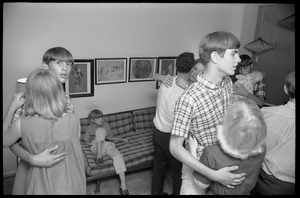 Teenage long hair: boys and girls slow-dancing at a teenage dance party, as a young boy watches from the couch