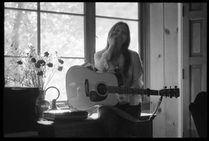 Judy Collins seated in a window at Joni Mitchell's house in Laurel Canyon, playing guitar