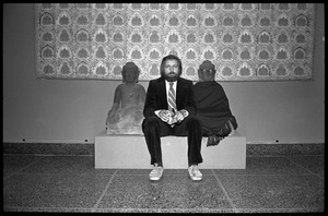 Rowland Scherman seated between Buddha sculptures while taking a break at the Birmingham Museum of Art