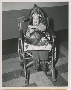 Young client in wheelchair wearing headdress and holding turkey