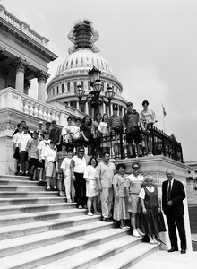 Congressman John W. Olver (right) with group of visitors, posed on the steps of the United States Capitol building (scaffolding on top of dome)