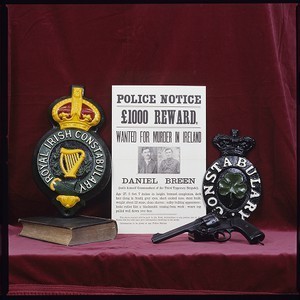 Shot of original "Dan Breen Wanted" poster beside police crests from an earlier era. Royal Irish Constabulary and Irish Constabulary