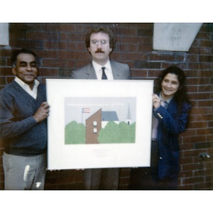Clara Garcia (right) and two men hold up a limited edition print that depicts Villa Victoria.