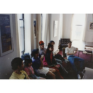 Teens and a younger child sitting in the Inquilinos Boricuas en Acción offices for pizza and a meeting of the Teen and Kid Empowerment Program.