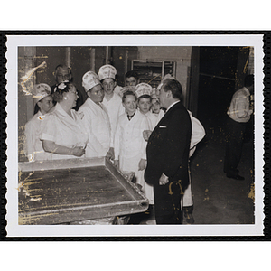 A man addresses members of the Tom Pappas Chefs' Club in a kitchen