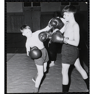 Two boys throw boxing punches at each other in the South Boston gymnasium