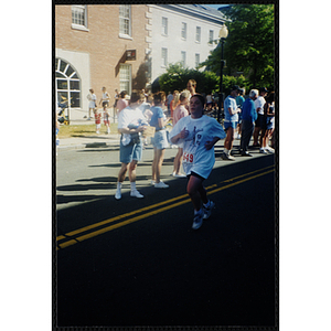 A woman runs by spectators during the Battle of Bunker Hill Road Race