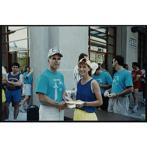 A man hands a woman a certificate as he shakes her hand during the Battle of Bunker Hill Road Race