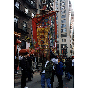 Man holds a decorative banner in a crowded street during a celebration of the Chinese New Year in Boston's Chinatown