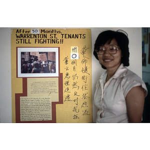 Suzanne Lee stands beside a sign at the Chinese Progressive Association that reads, "After 30 months, Warrenton St. Tenants Still Fighting!!"