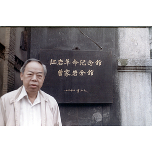 Association member poses in front of a Chinese plaque