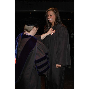 Faculty member presents student with pin at School of Nursing pinning ceremony during convocation