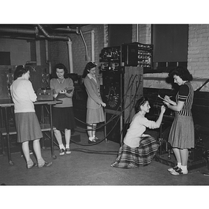 Five women test equipment in an electrical engineering laboratory