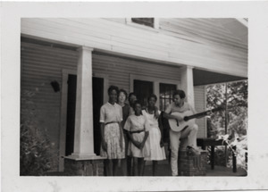White civil rights worker playing guitar on the front steps of the Freedom House (Marjorie Merrill, 2d from left)