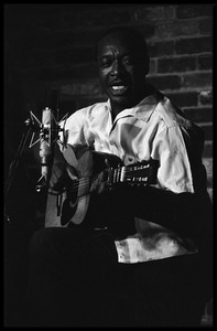 Josh White performing on guitar in a coffeehouse