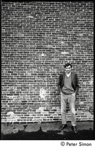 Howard Zinn: full-length portrait standing against a brick wall