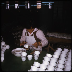 Ceramics factory: woman applying transfer design to tea cups
