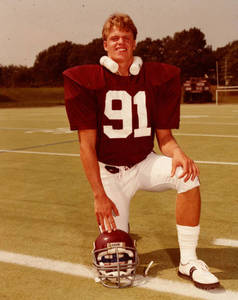 Bill Delaney kneeling on football field