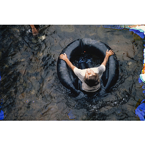 Child floating in shallow water on tire