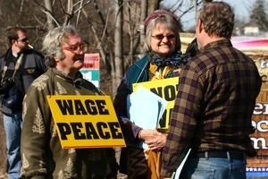 Protesters talking, one wearing a sign reading 'Wage peace': rally and march against the Iraq War