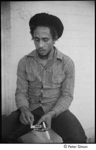 Bob Marley holding a joint the steps of his home