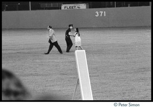 Policeman confronts a young girl rushing the field at Shea Stadium during the Beatles concert