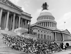 Congressman John W. Olver (right) and visitors, posed on the steps of the United States Capitol building (scaffolding on top of dome)