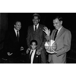 Mayor Raymond Flynn holds a basketball while standing with two men and a boy