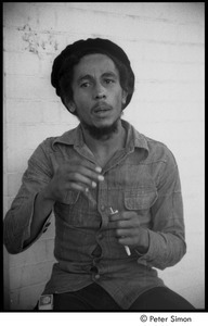 Bob Marley holding a joint the steps of his home