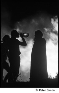 After the Maypole celebration, Packer Corners commune: silhouette and bonfire, with man drinking wine from a bottle