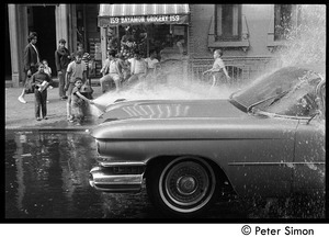 Children playing in the spray of an opened fire hydrant in front of Bayamon Grocery, Spanish Harlem