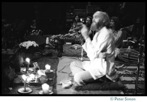 Ram Dass seated onstage at the Winterland Ballroom during his 'marathon,' addressing the audience