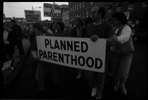 Planned Parenthood escorts with banner passing pro-life protesters in front of the Providence Planned Parenthood clinic