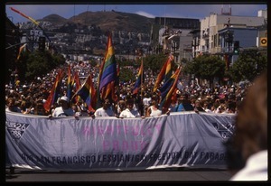 Massive crowd approaching during the San Francisco Pride Parade, carrying pride flags and banner reading 'Rightfully proud'