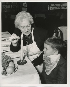 Older woman lighting a candle for a young client at Thanksgiving celebration