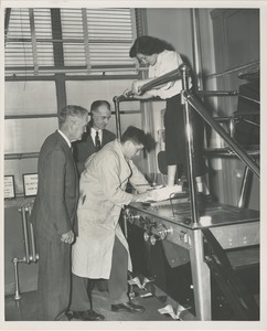 A technician makes a mold of a woman's foot for a prosthetic device as two men, including Bruce Barton, look on