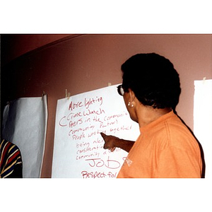 Man pointing to items on a list of suggestions generated during a community meeting.