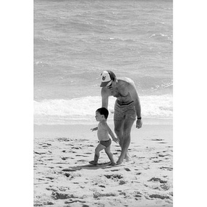 Unidentified man with a toddler at the beach.