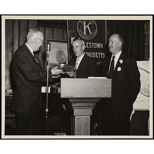 Two men present an award at the podium at the Kiwanis Club's Bunker Hill Postage Stamp Luncheon