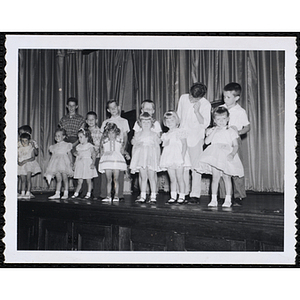 Seven girls and their brothers standing together on the stage during a Boys' Club Little Sister Contest