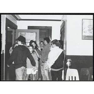 Children gather by a door with site coordinators Liz Cinquino and Josh Kraft at the Tri-Club slide show at the Charlestown Clubhouse