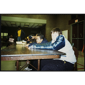 Boys sit at a table with pencils and papers at a Tri-Club event