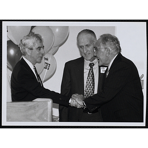Ronald M. Ansin, at right, shaking hands with an unidentified man while Edmund Ansin looks on at the opening of Ansin Youth Center