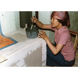 Chinese Progressive Association member paints a pipe as part of a building renovation project