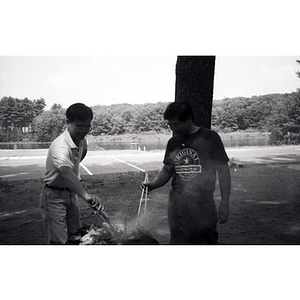 Two men flip cook on a grill at a Chinese Progressive Association picnic